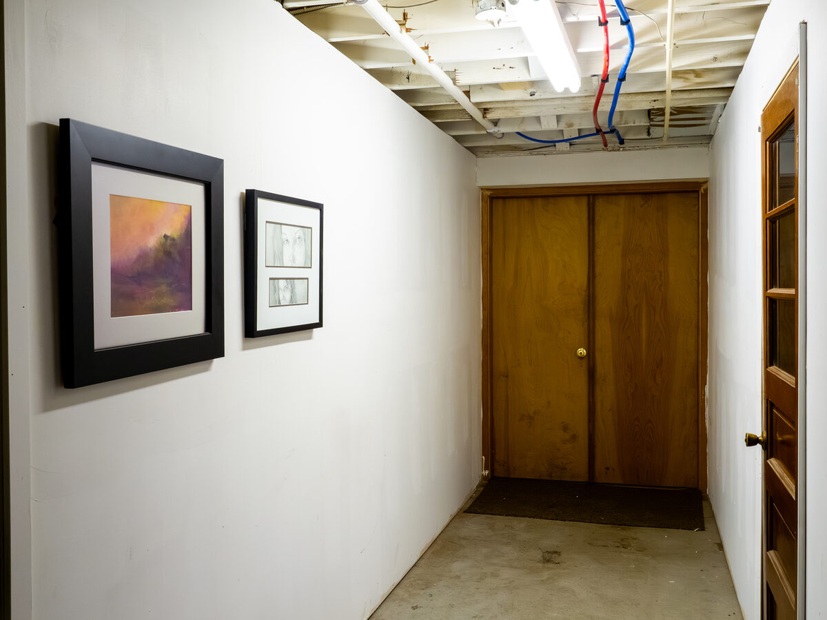 Where the building meets the loading bays. Raw ceiling, soft light, two small paintings.