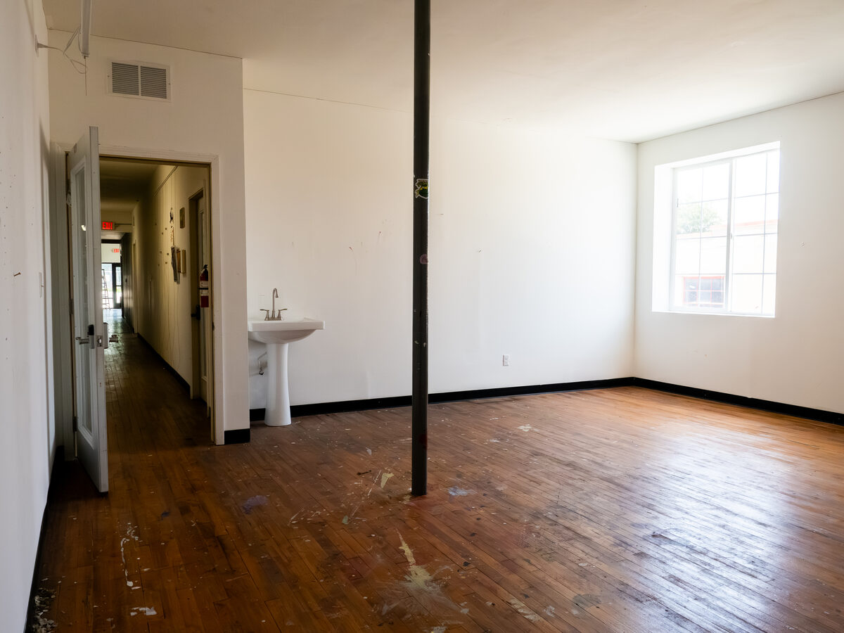 A fresh studio — refinished hardwood, a porcelain sink, a south-facing window, white walls waiting on you.