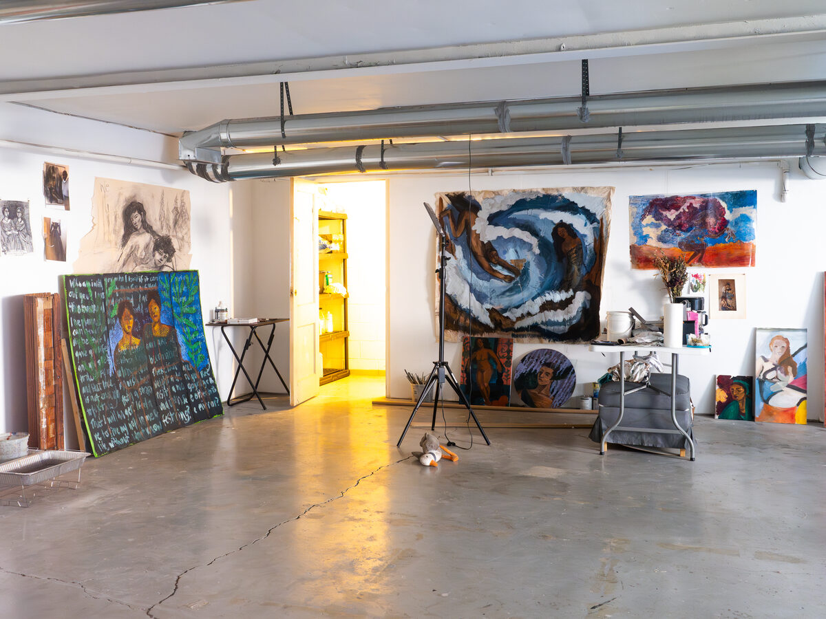 A larger studio set up for big canvases and oversized work, with side daylight from the loading bays.